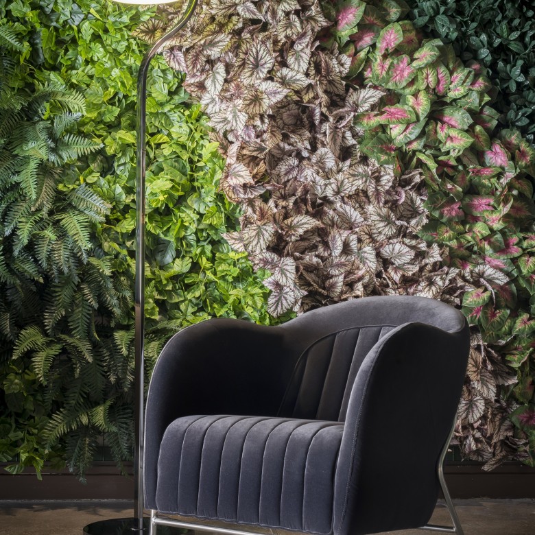 Silla colocada delante de un muro verde artificial