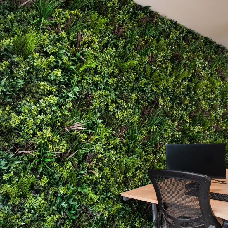 Silla colocada delante de un muro verde artificial