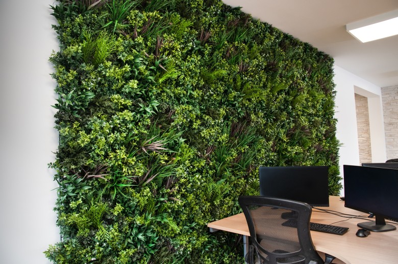 Silla colocada delante de un muro verde artificial